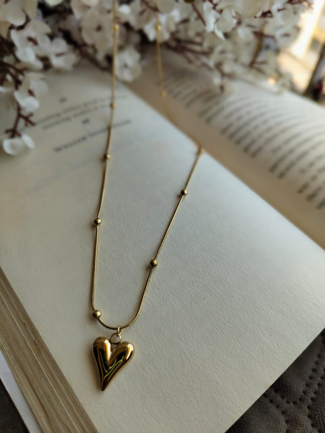 polished heart pendant on a chain with small bead accents.